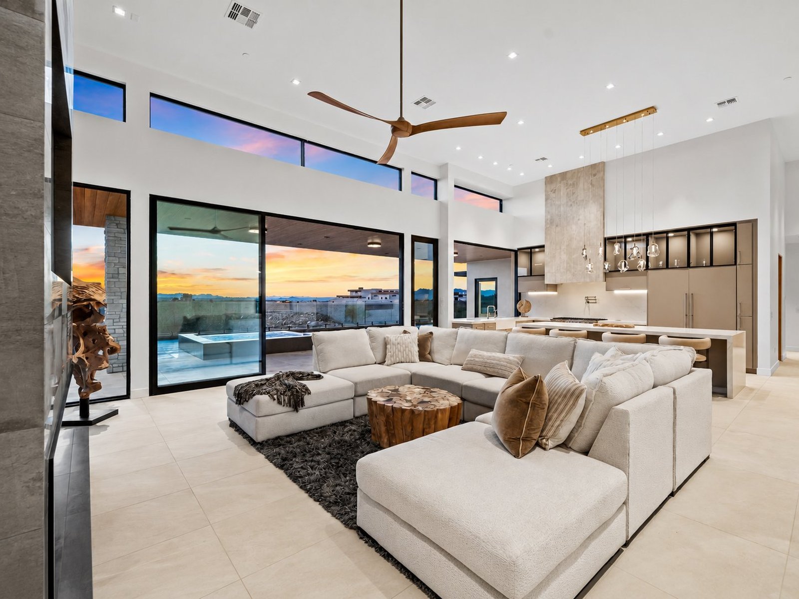 A Janecek custom great room opening to a sunset desert view through full-height glass