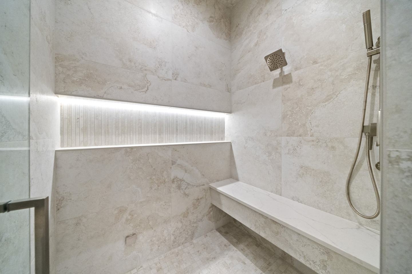 Marble walk-in shower with a lit stone niche