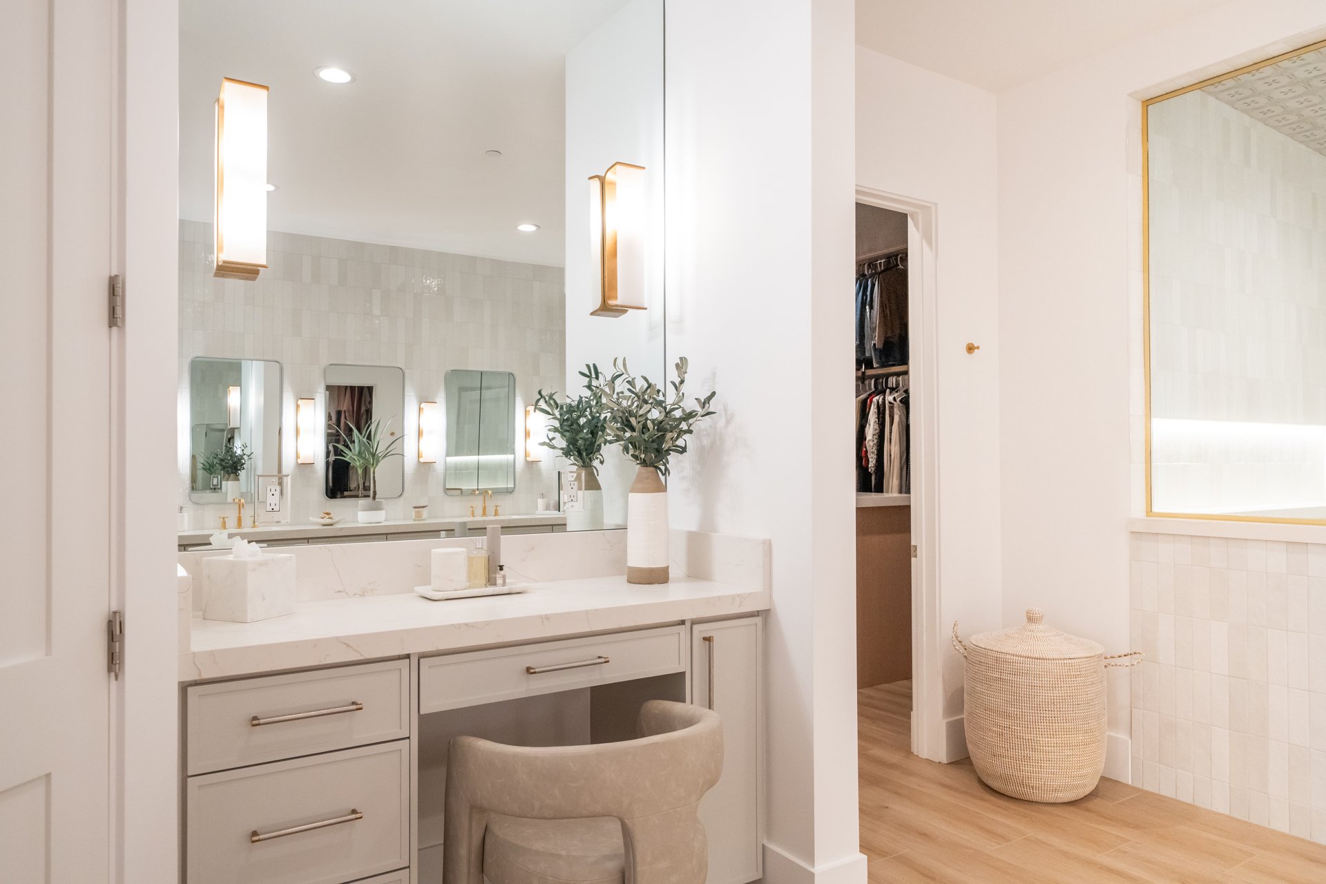 Makeup vanity nook with brass sconces, quartz counters, and walk-in closet beyond