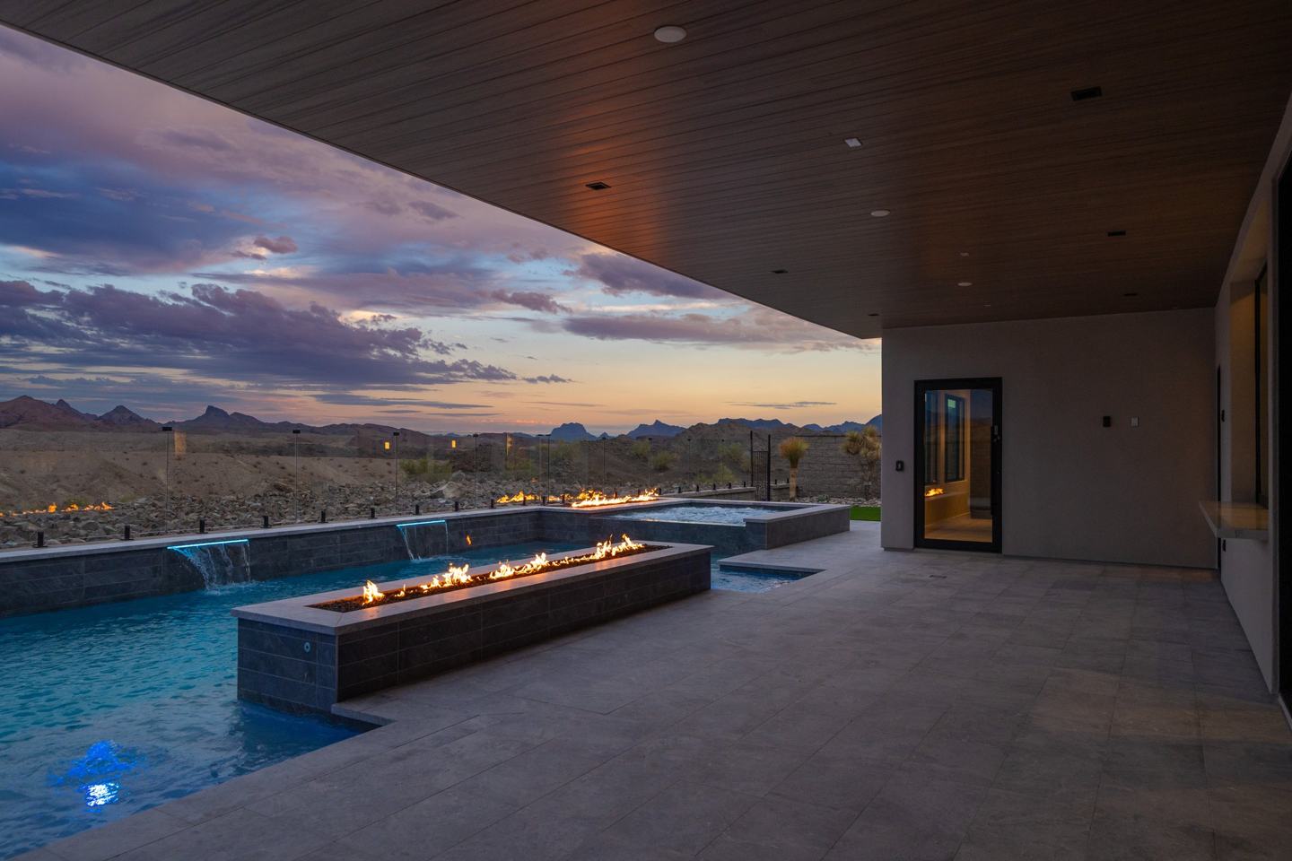 Custom Janecek home patio at sunset with fire features, pool, and desert mountain views