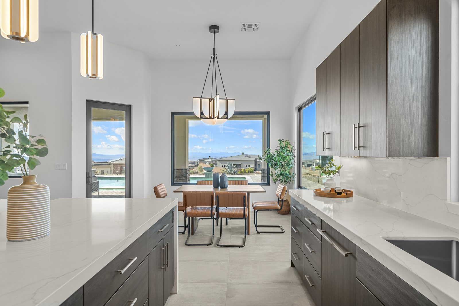 Kitchen with full-slab marble backsplash, dark wood cabinetry, and a dining nook framing a desert view
