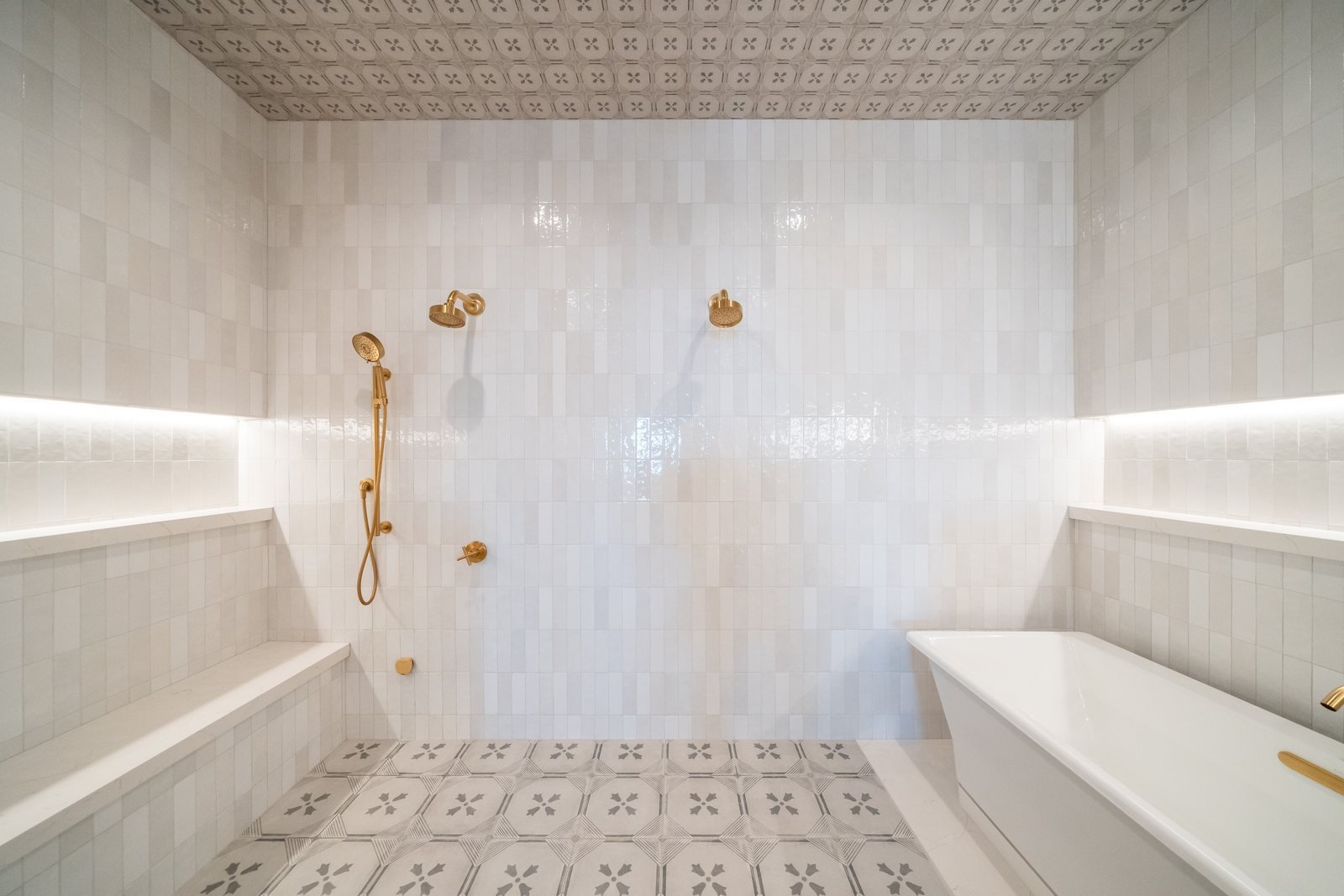 Walk-in double shower with patterned cement-tile floor and ceiling, zellige walls, and brushed-gold fixtures