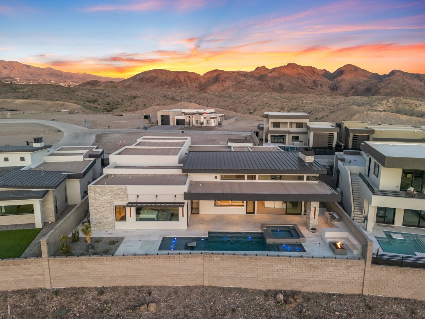 Aerial rear view of the estate with pool, spa, and desert mountains at dusk