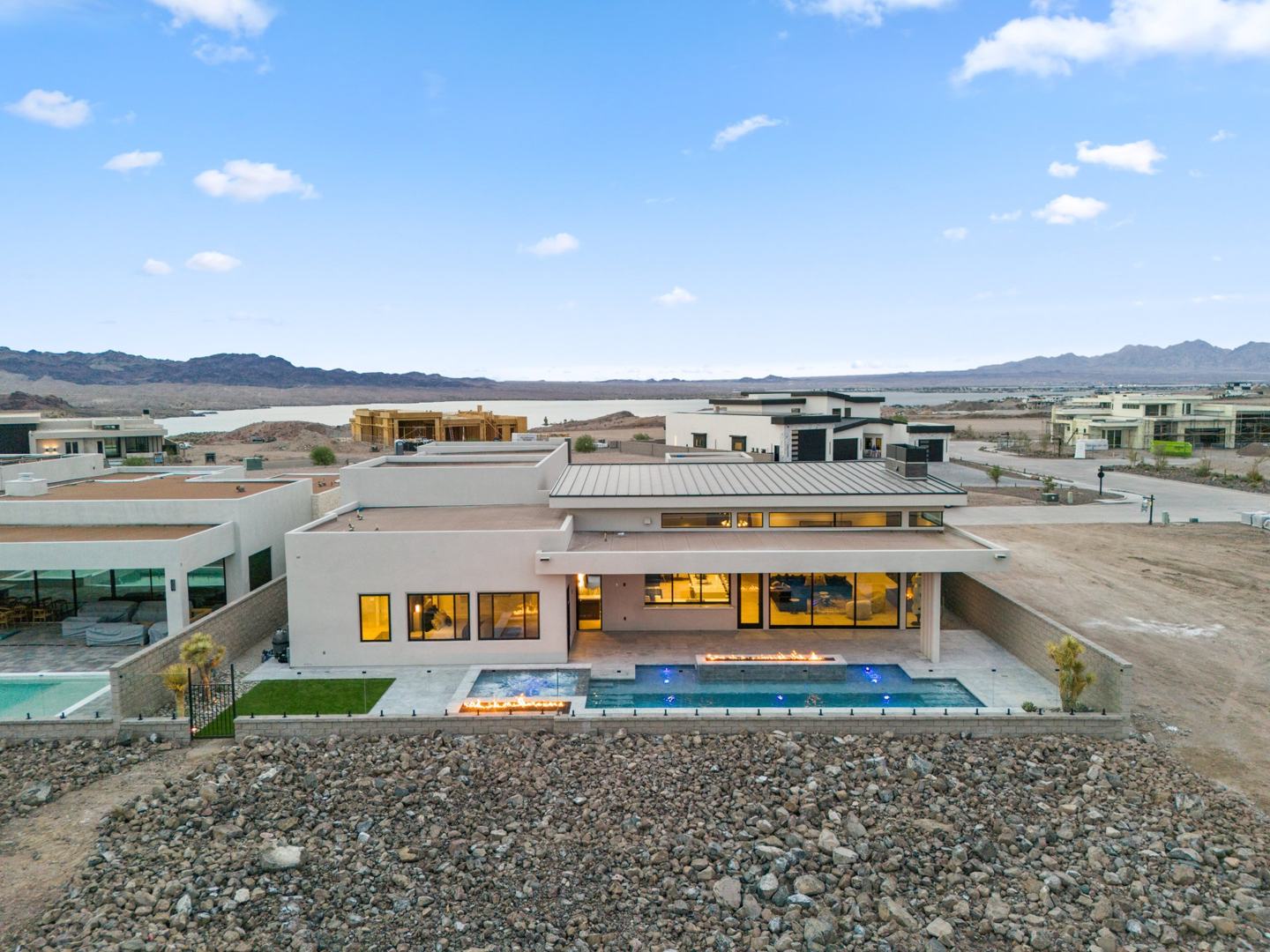 Rear elevation at dusk with pool, spa, and linear fire features