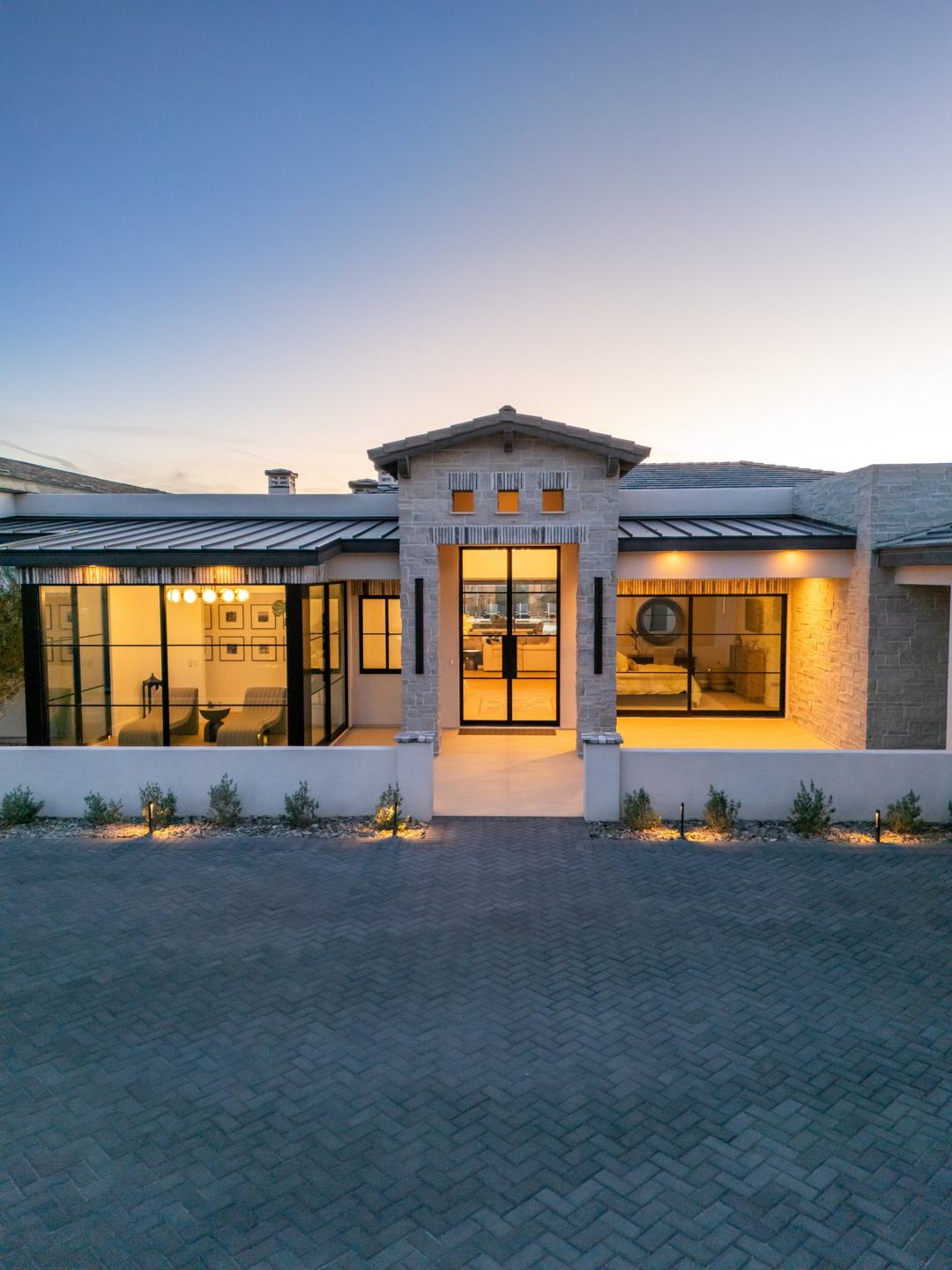 Illuminated stone and glass front entry of a custom home at dusk