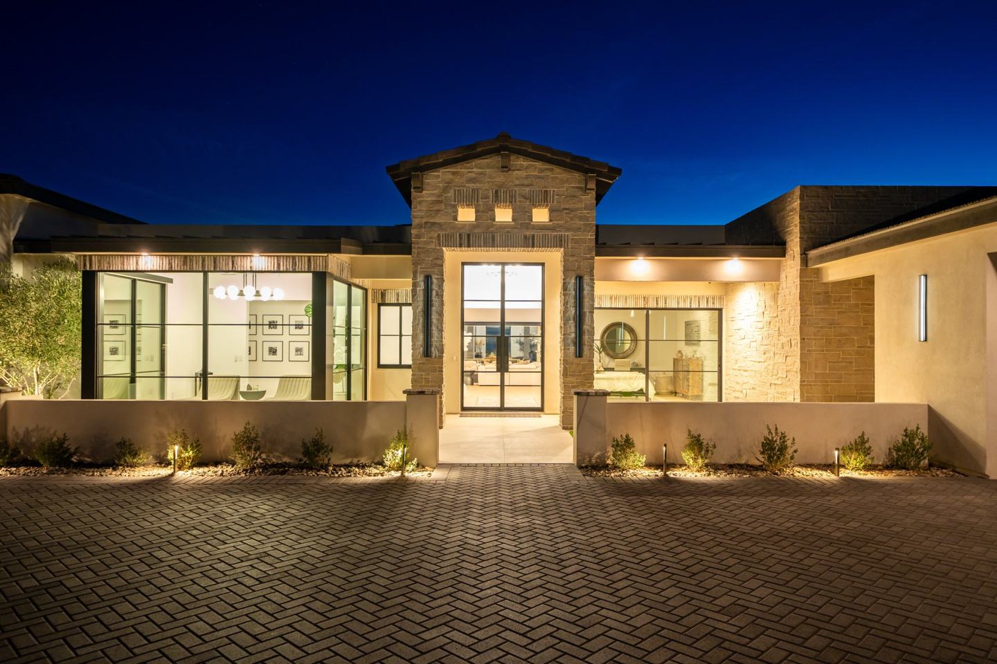 Stone entry tower with steel and glass doors glowing at twilight