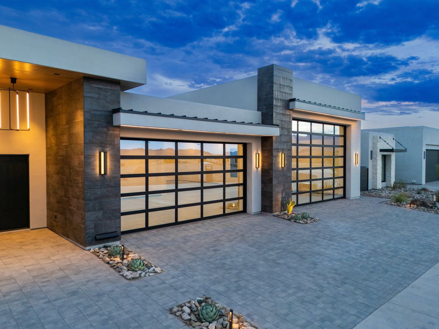 Full view glass garage doors on a modern desert custom home at dusk