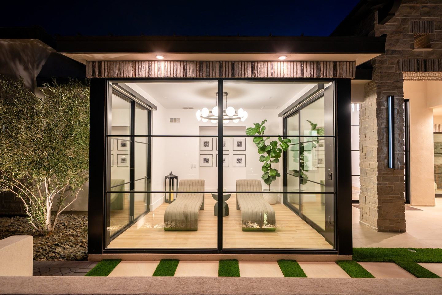 Illuminated glass walled sitting room viewed from the courtyard at night