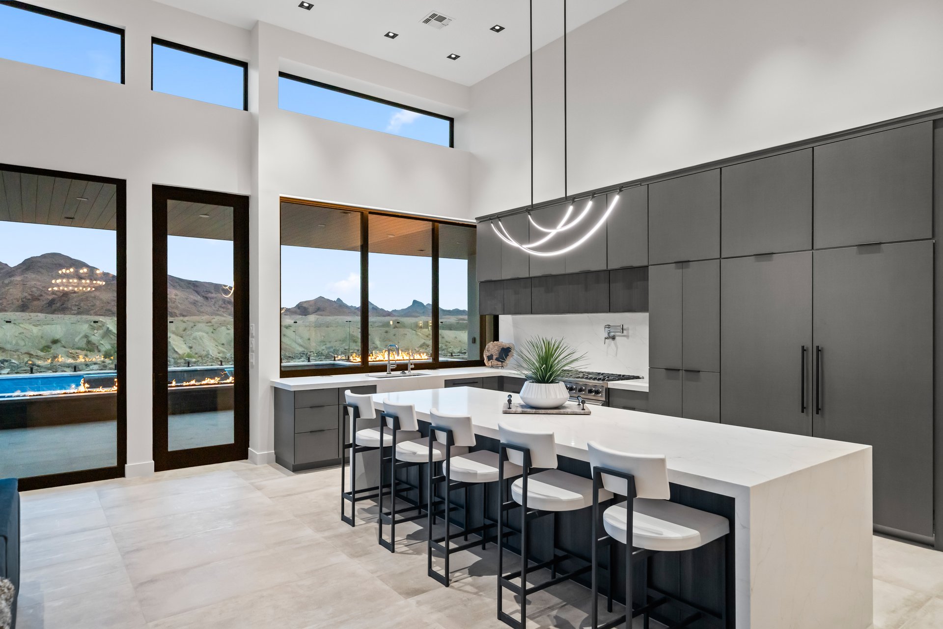 Chef kitchen with charcoal cabinets, a marble waterfall island, and desert views