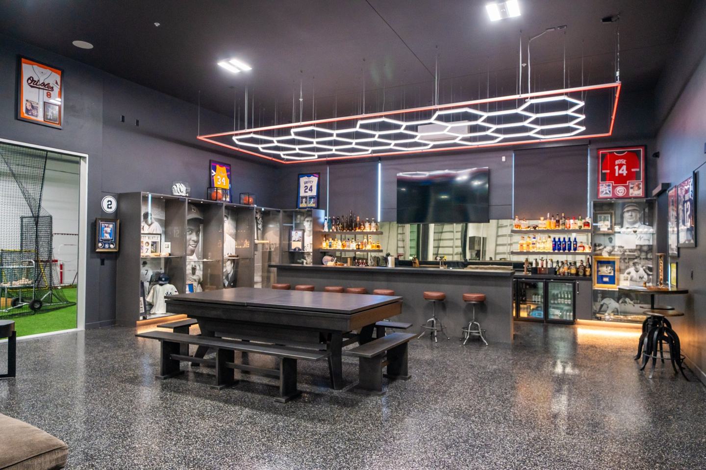 Memorabilia bar with hexagon lighting, display cases, and a game table