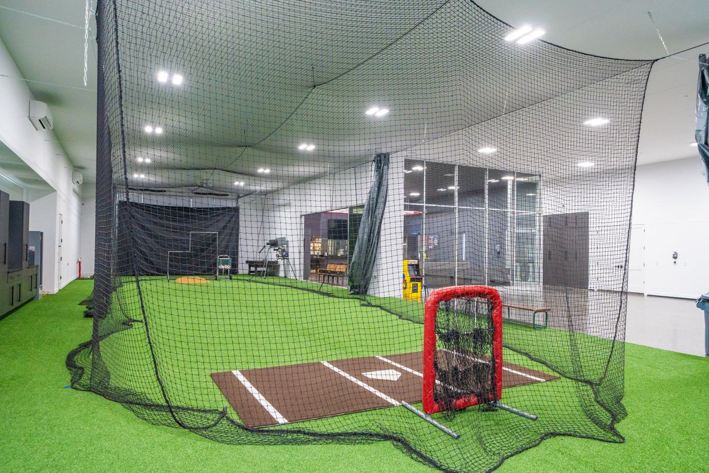 Home plate and pitching screen inside a private indoor batting cage
