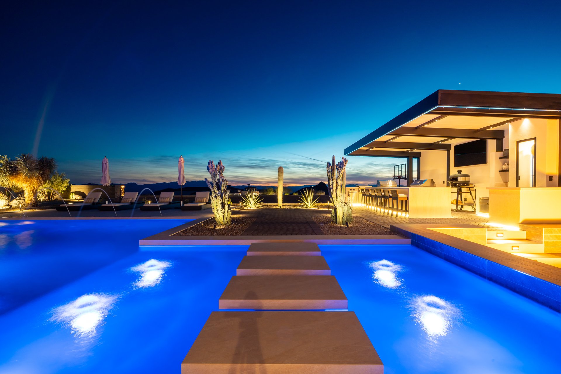 Pool with a stepping stone path and outdoor bar at twilight