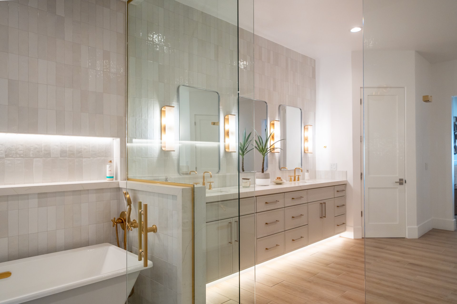 Primary bathroom with a double vanity, freestanding tub, and gold fixtures