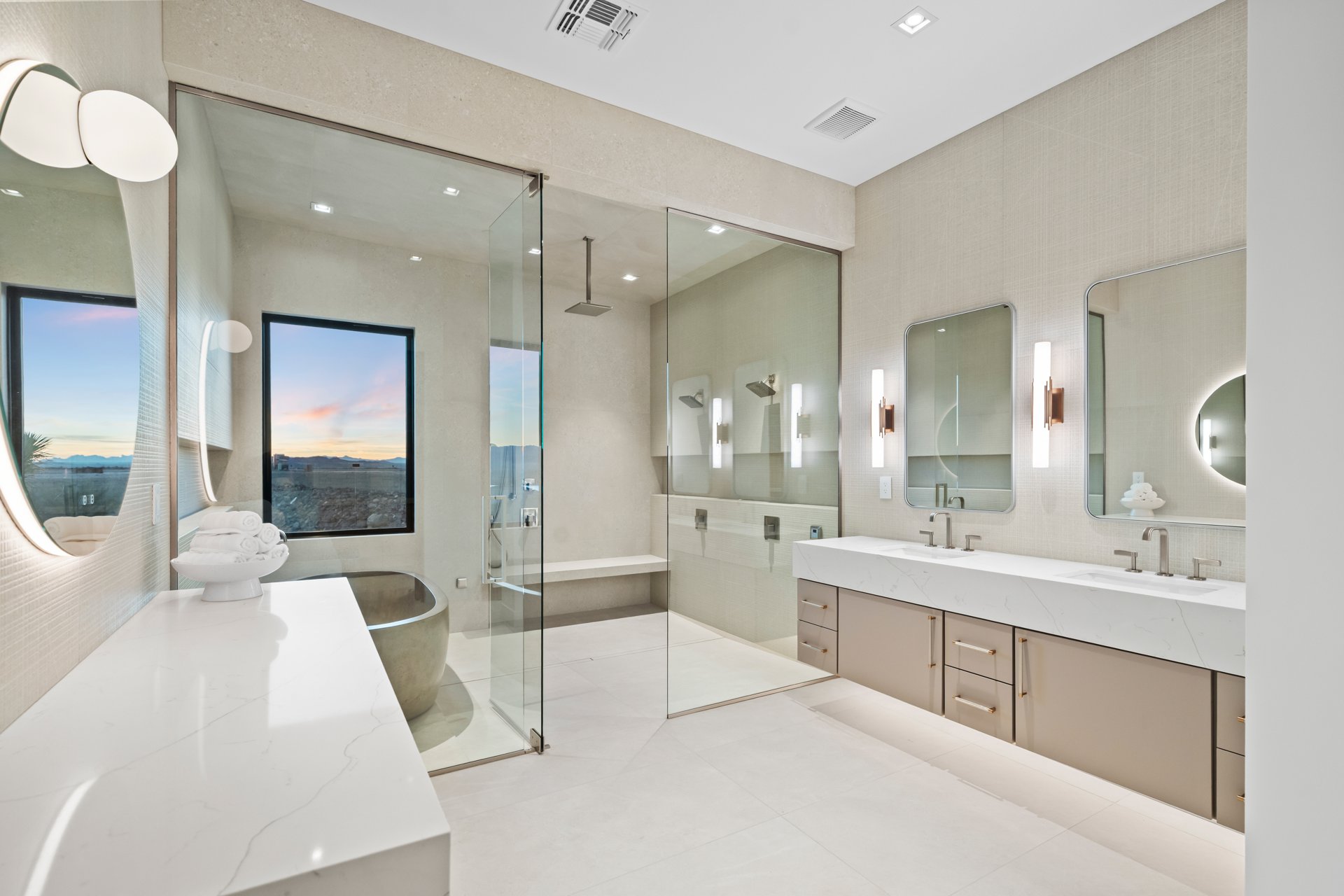 Primary bath with a stone soaking tub, glass shower, and sunset views through the window