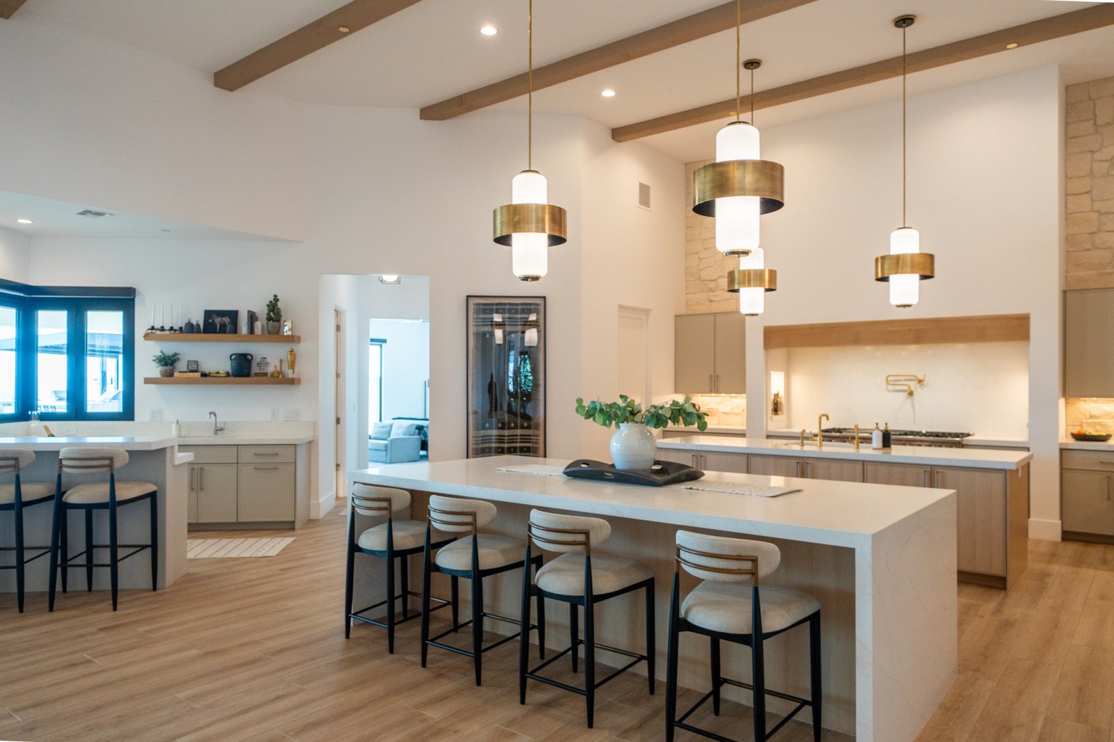 A Janecek custom home interior with open kitchen, brass pendants, and wood beams