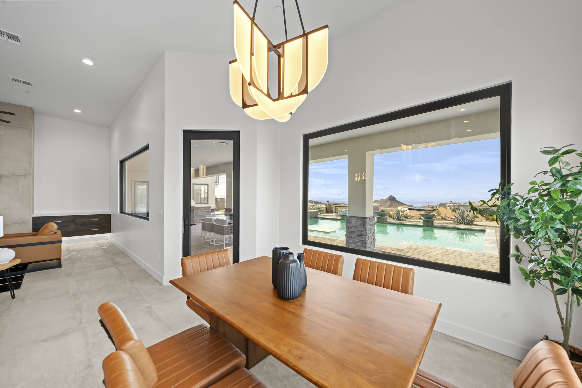 Dining area with a wood table and picture window framing the pool and desert