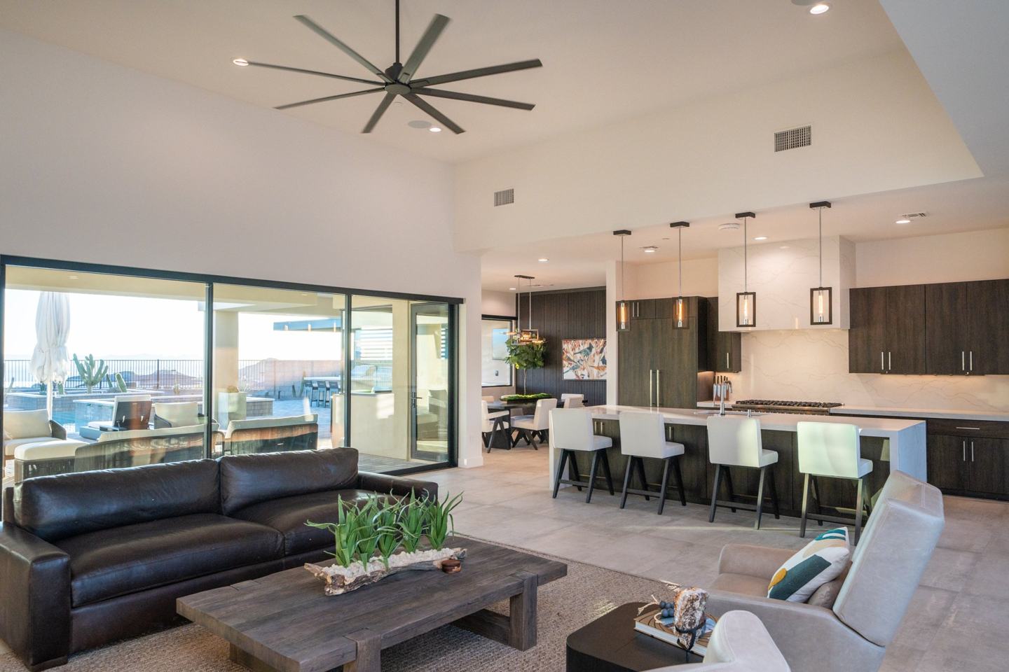 Great room with a leather sectional opening to the kitchen island and covered patio