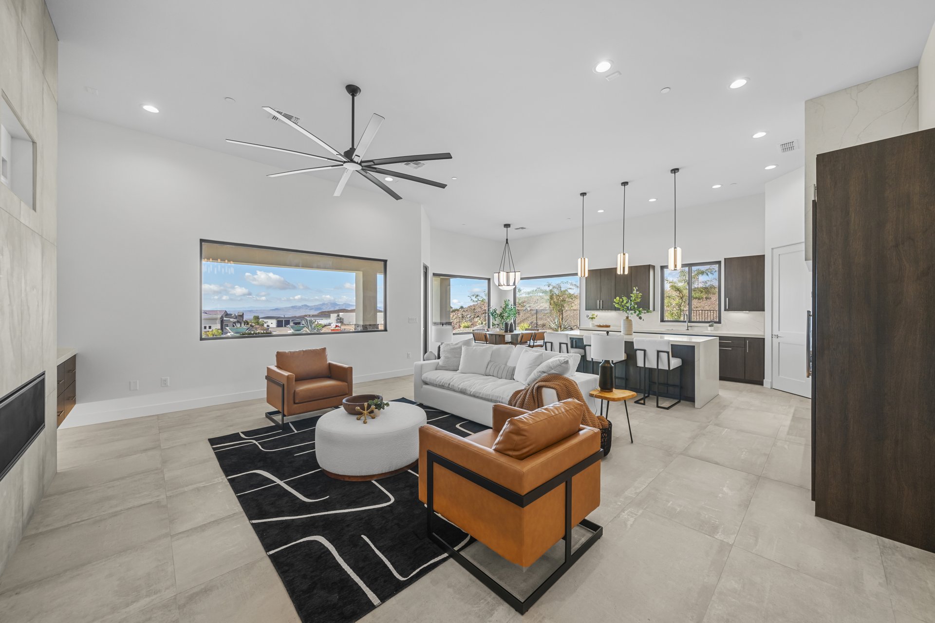 Open concept living room and kitchen with leather accent chairs and desert views