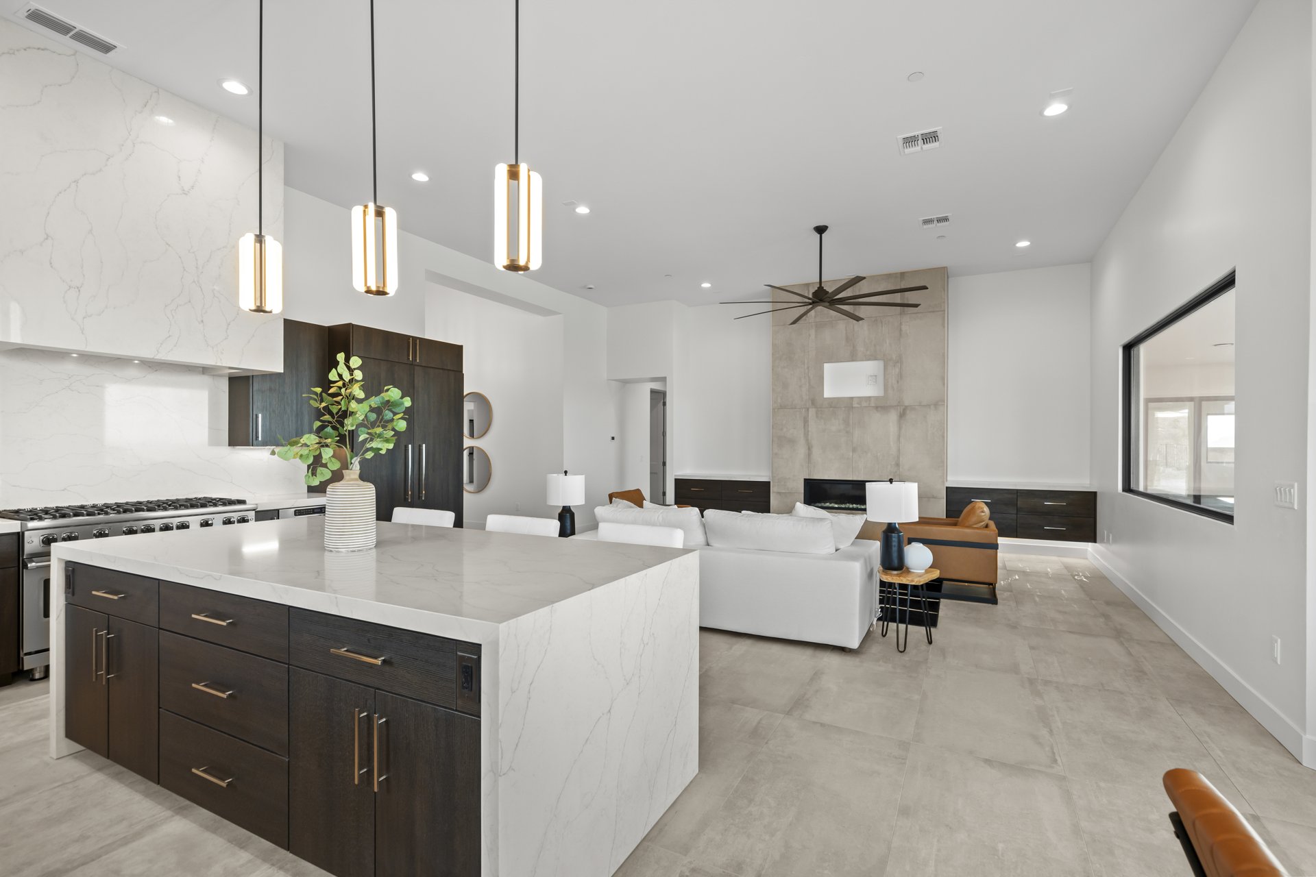 Open kitchen with a marble waterfall island flowing into the great room