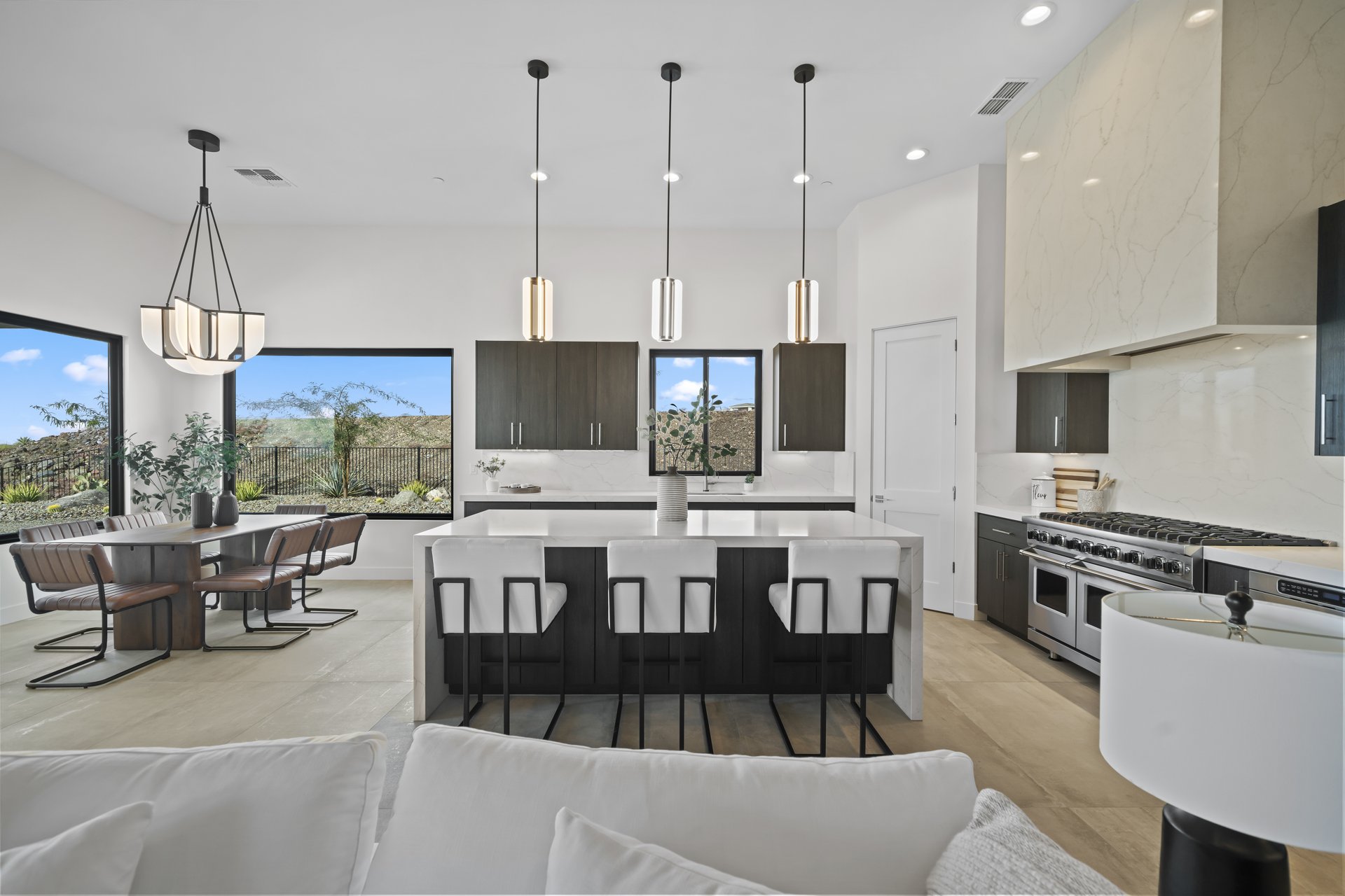 White quartz island kitchen with pendant lighting and dining area with desert views
