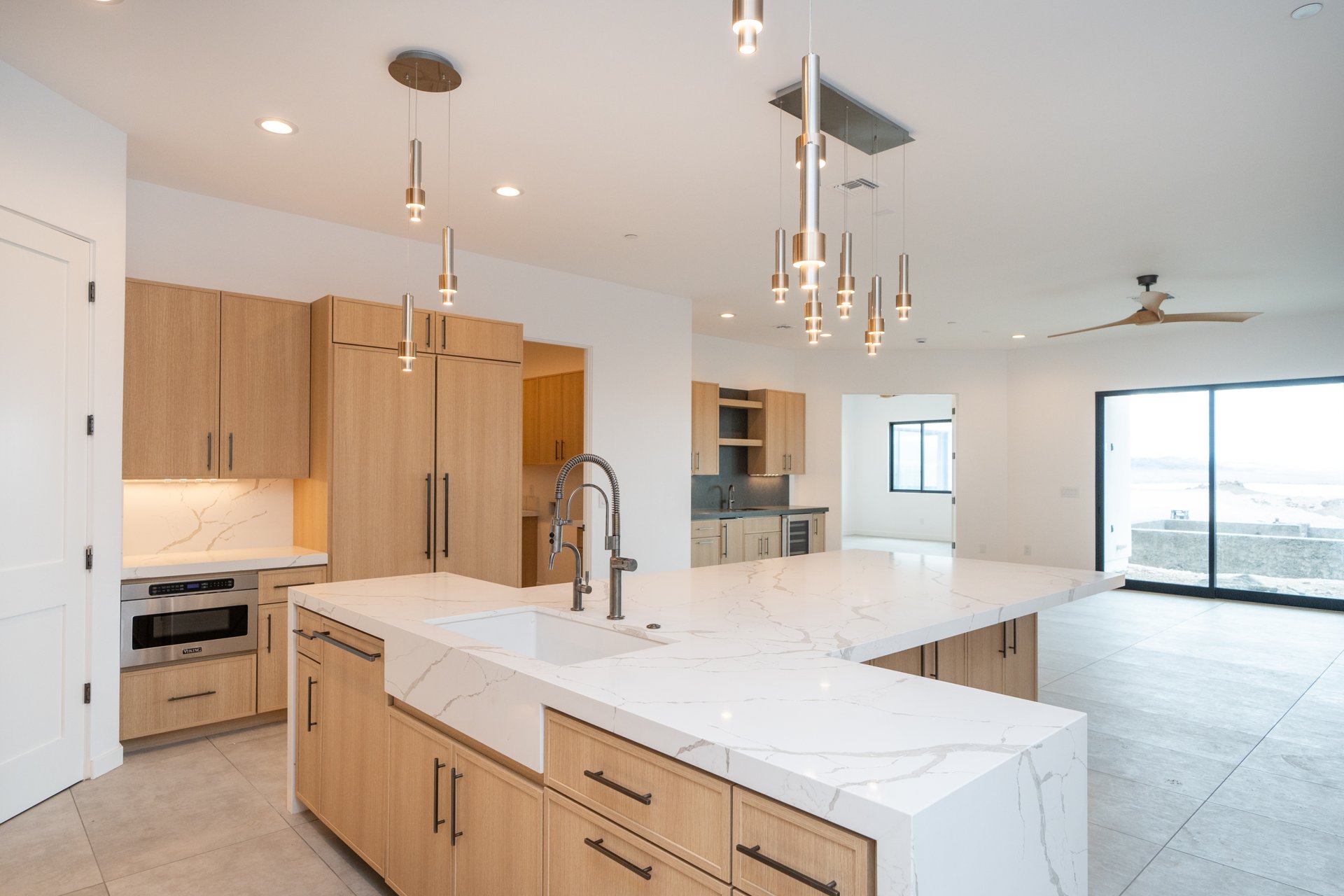 White oak kitchen with a double island, farmhouse sink, and marble counters