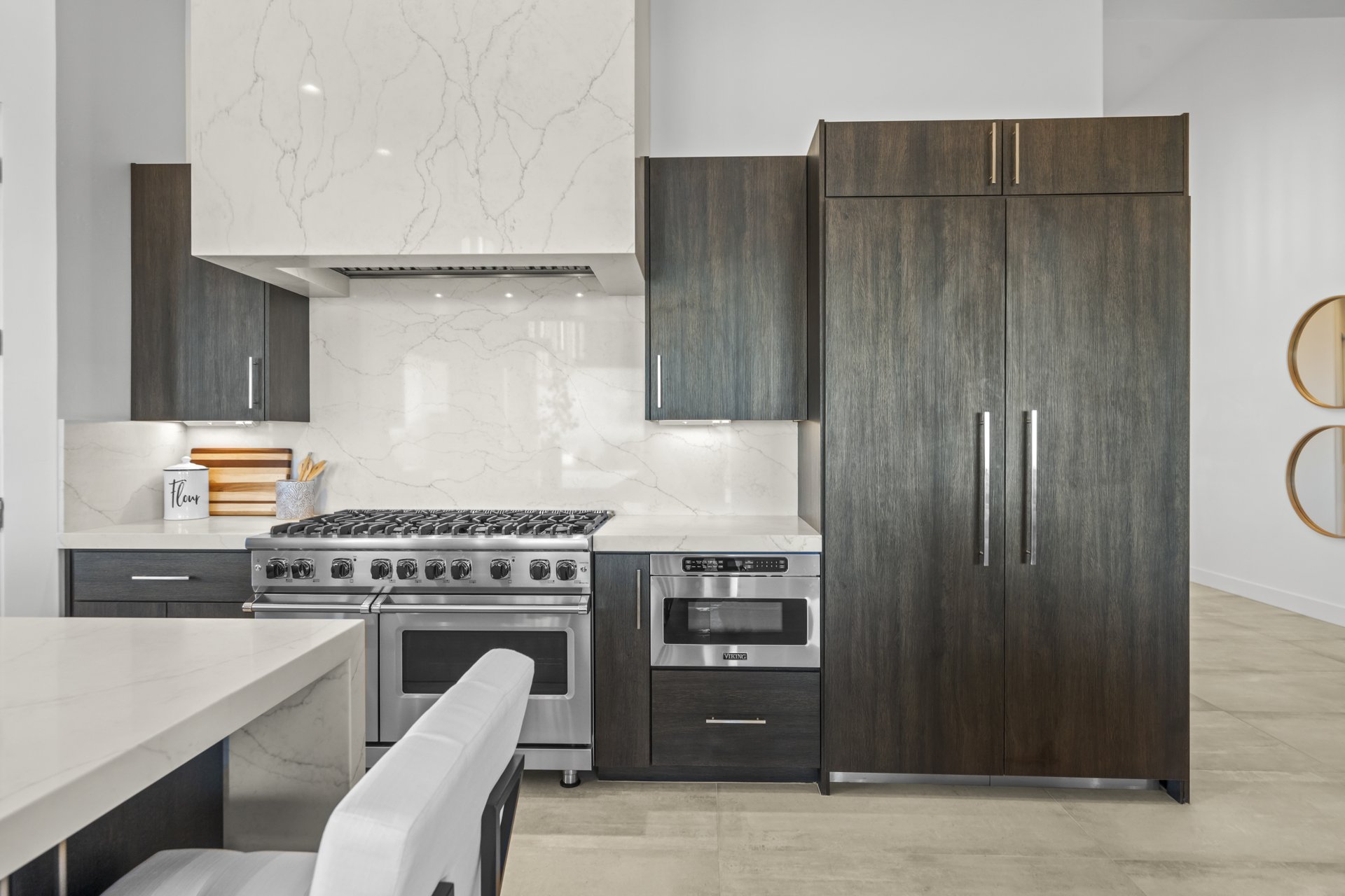 Kitchen range wall with quartz hood, pro-style range, and panel front refrigerator columns
