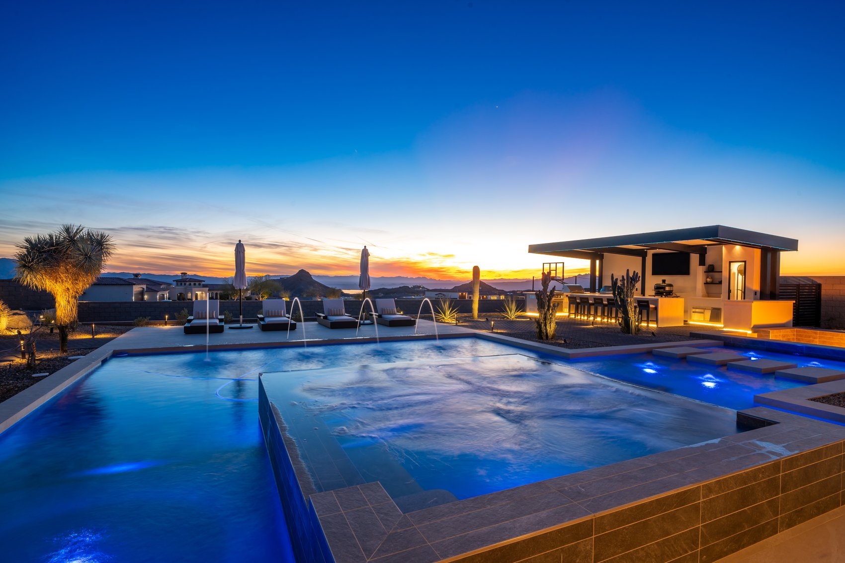 A Janecek backyard at twilight with an infinity pool and outdoor living above Lake Havasu