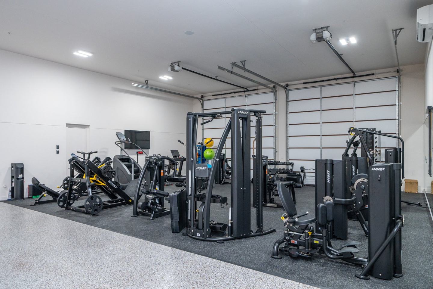 Private gym with commercial strength machines, dumbbells, and cardio equipment
