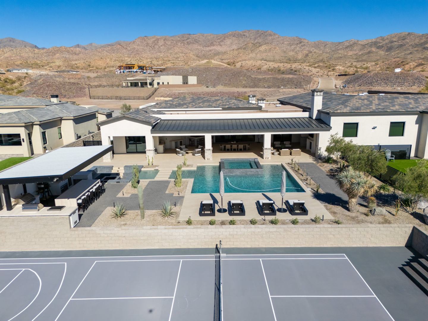 Aerial view of the backyard pool, loungers, and private sport court