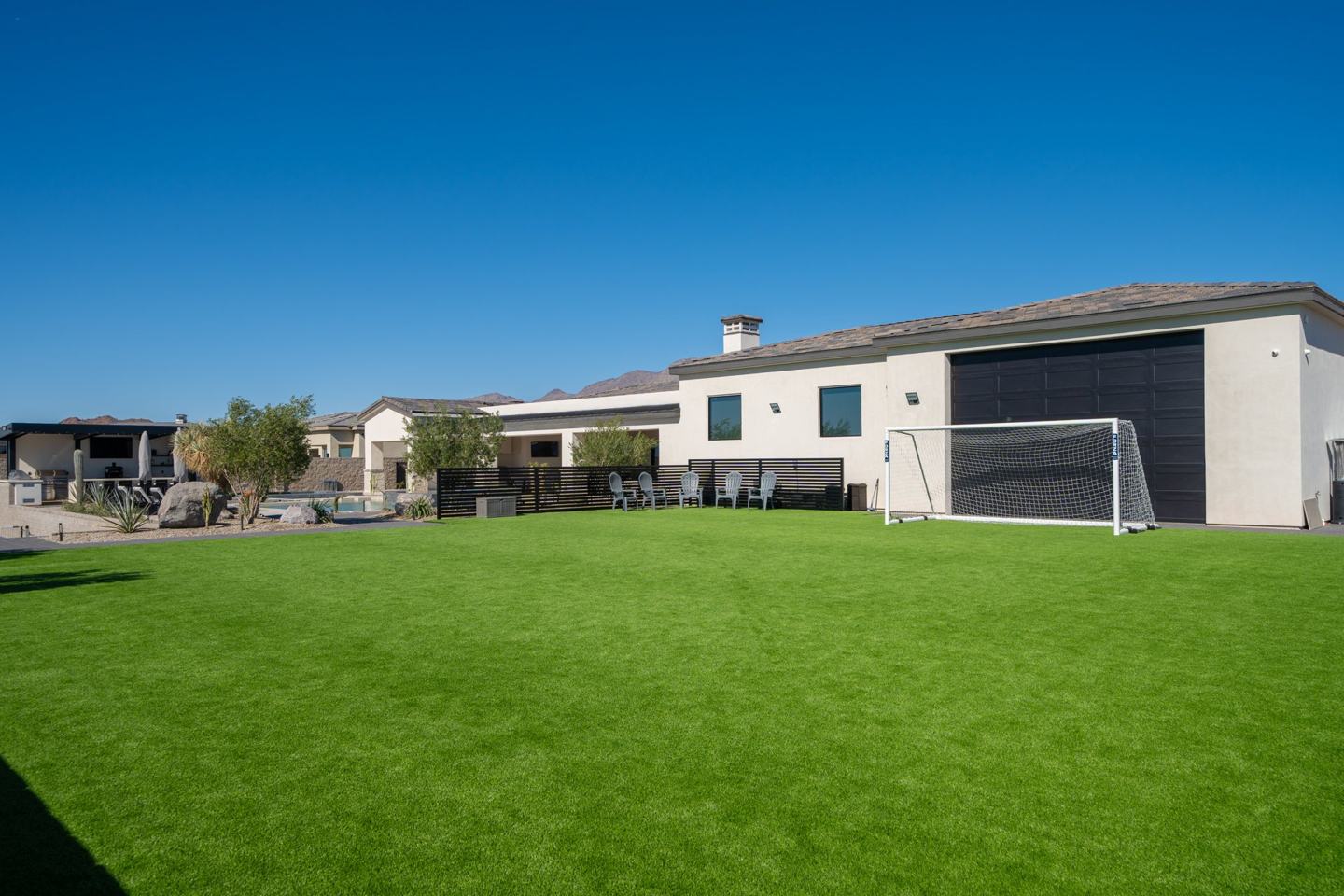 Private backyard turf sports lawn with a soccer goal beside the pool terrace