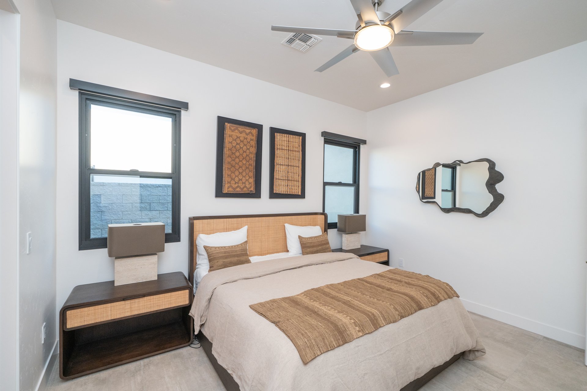 Guest bedroom with a rattan headboard, woven wall art, and organic mirror
