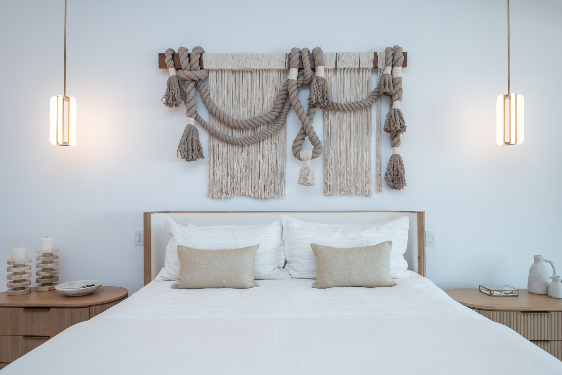 Bedroom with a woven rope and macrame wall hanging above a white oak bed
