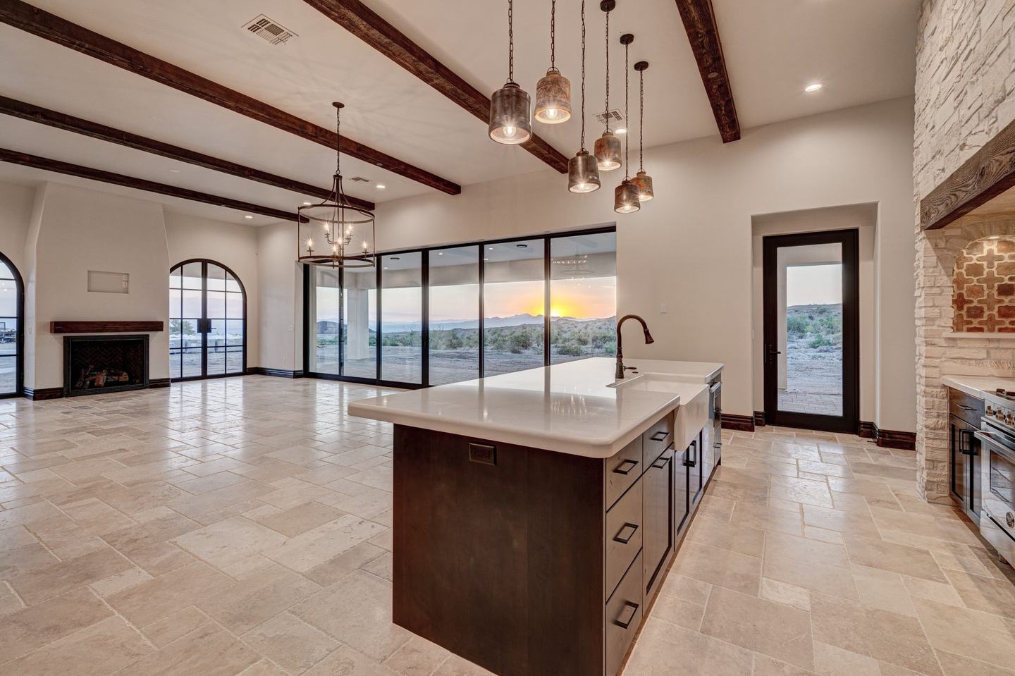 Great room and kitchen opening to the desert sunset through a wall of glass